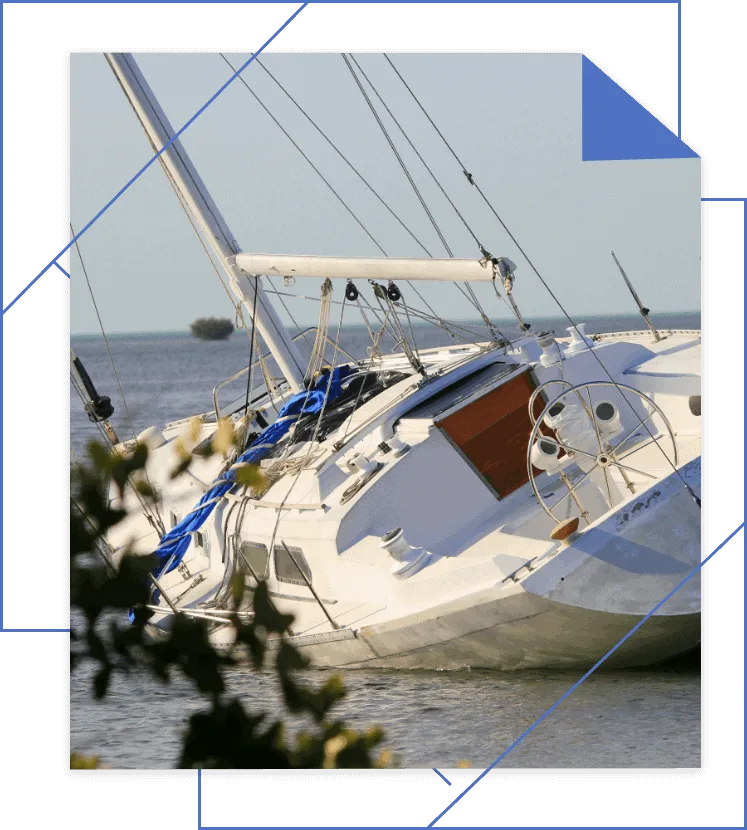 Capsized sailboat partially submerged near the shoreline.