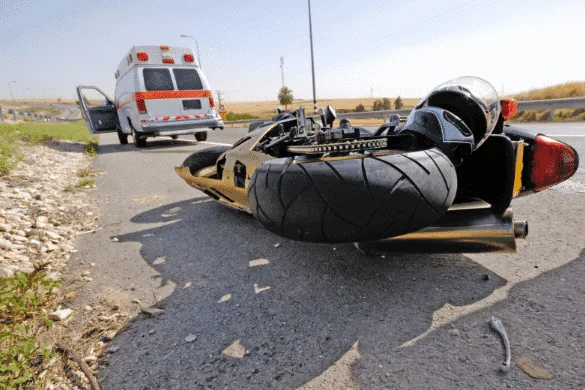 An overturned motorcycle lay on the road, with an ambulance parked nearby. If you're seeking a Detroit motorcycle accident attorney for legal help after such incidents, consider reaching out to experienced professionals who understand your needs.