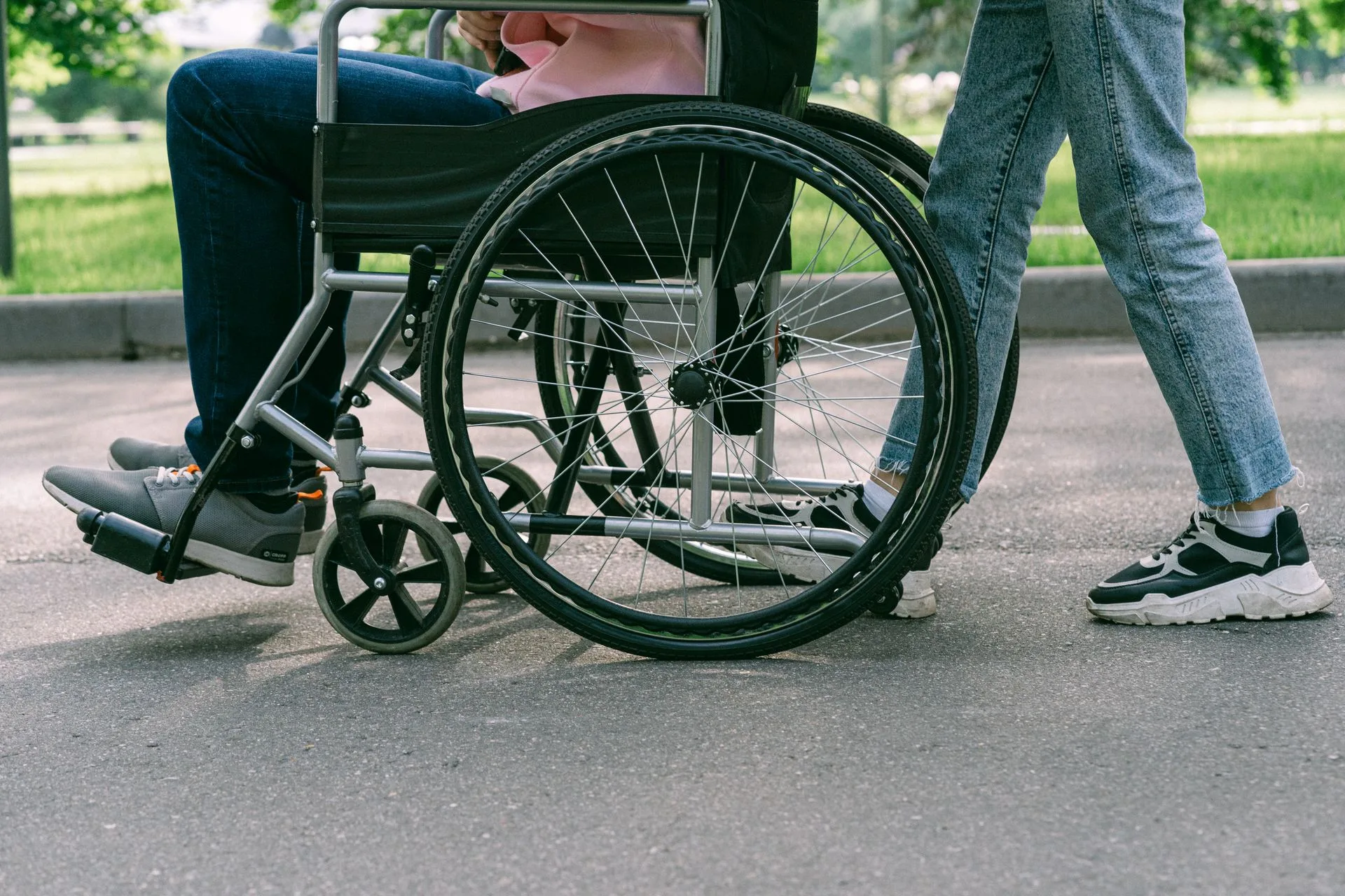 Person in a wheelchair being pushed along a paved path
