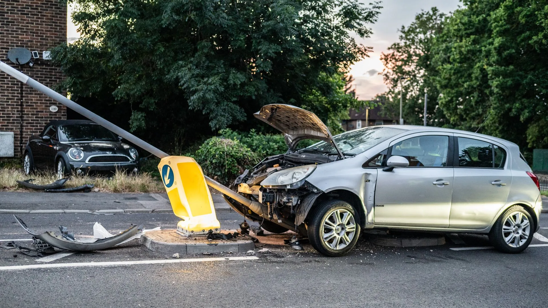 Silver hatchback with a crumpled front end after hitting a traffic bollard