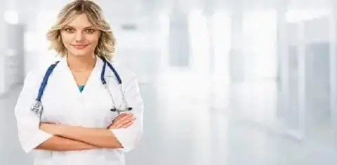 A person wearing a white coat and stethoscope stands confidently in a bright medical facility, ready to provide expert medical care.