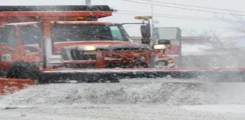 A snow plow efficiently clears the road during a heavy snowfall, ensuring safe passage and preventing potential truck injuries.