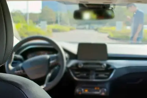 From the driver's seat, the dashboard and steering wheel come into view. Through the windshield, a person stands on the road, evoking scenes from countless self-driving car accidents that have sparked intense discussions like those in the ongoing GM Cruise lawsuit.