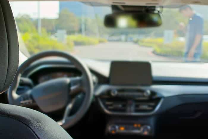 From the driver's seat, the dashboard and steering wheel come into view. Through the windshield, a person stands on the road, evoking scenes from countless self-driving car accidents that have sparked intense discussions like those in the ongoing GM Cruise lawsuit.