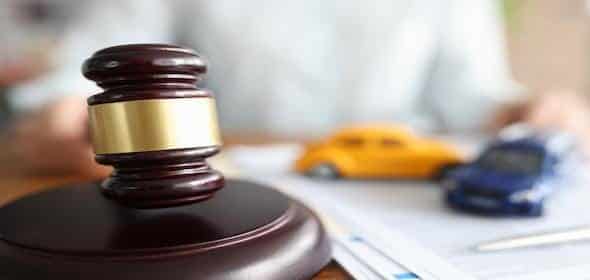 A judge's gavel rests on a table near two toy cars and documents, hinting at a legal scenario involving Michigan car accidents and the state's statute of limitations.
