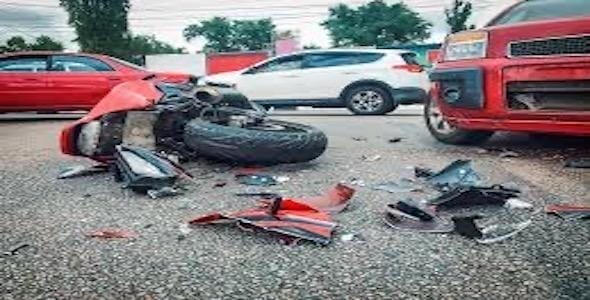 A motorcycle lies on its side, surrounded by debris in a Michigan parking lot, next to a red car. This scene highlights the unfortunate realities and causes of motorcycle accidents.