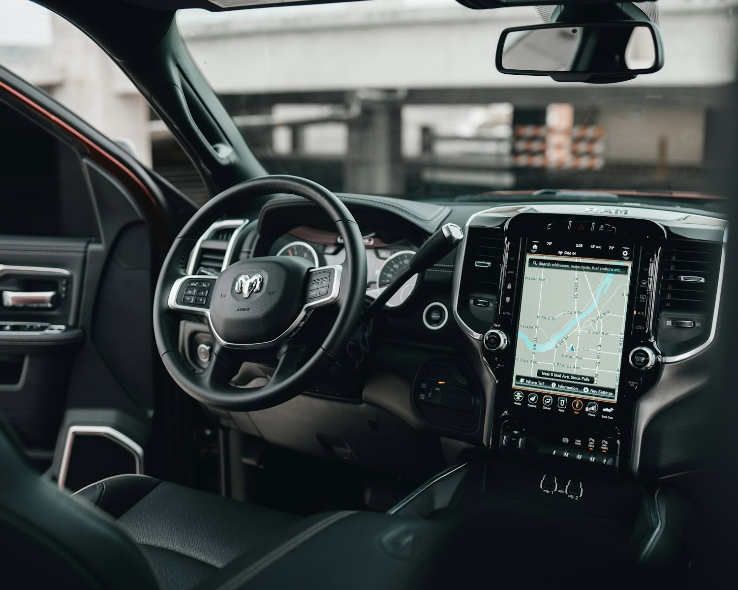 Interior view of a modern pickup truck showing the steering wheel, dashboard, and large central touchscreen display with navigation map—ideal for discussing autonomous vehicle liability or consulting a lawyer after a self-driving car accident in Michigan.