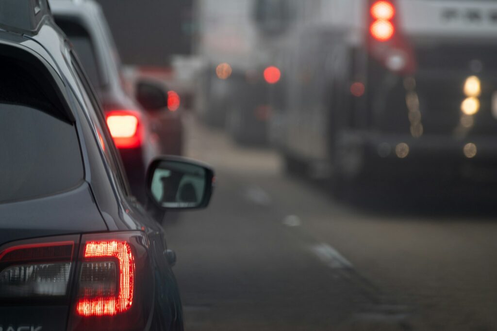 Cars and buses are stopped in traffic on a road, brake lights illuminated, evoking concerns about Michigan traffic fatalities amid the scene's slight blur.