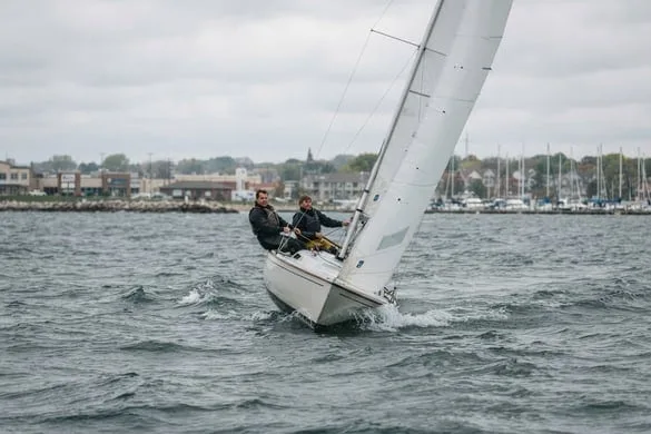 Sailboat heeling sharply in choppy water near a marina, representing boating accidents